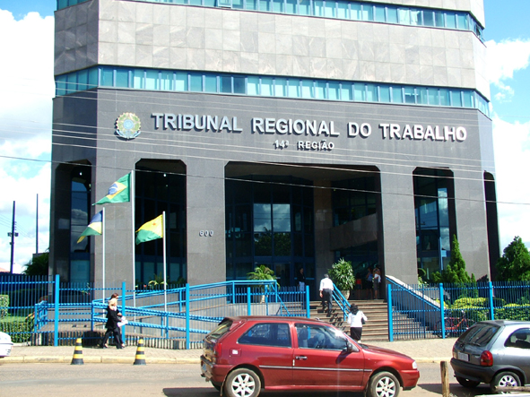 A imagem mostra a fachada do TRT da 14ª Região (RO/AC) com algumas pessoas entrando no prédio.