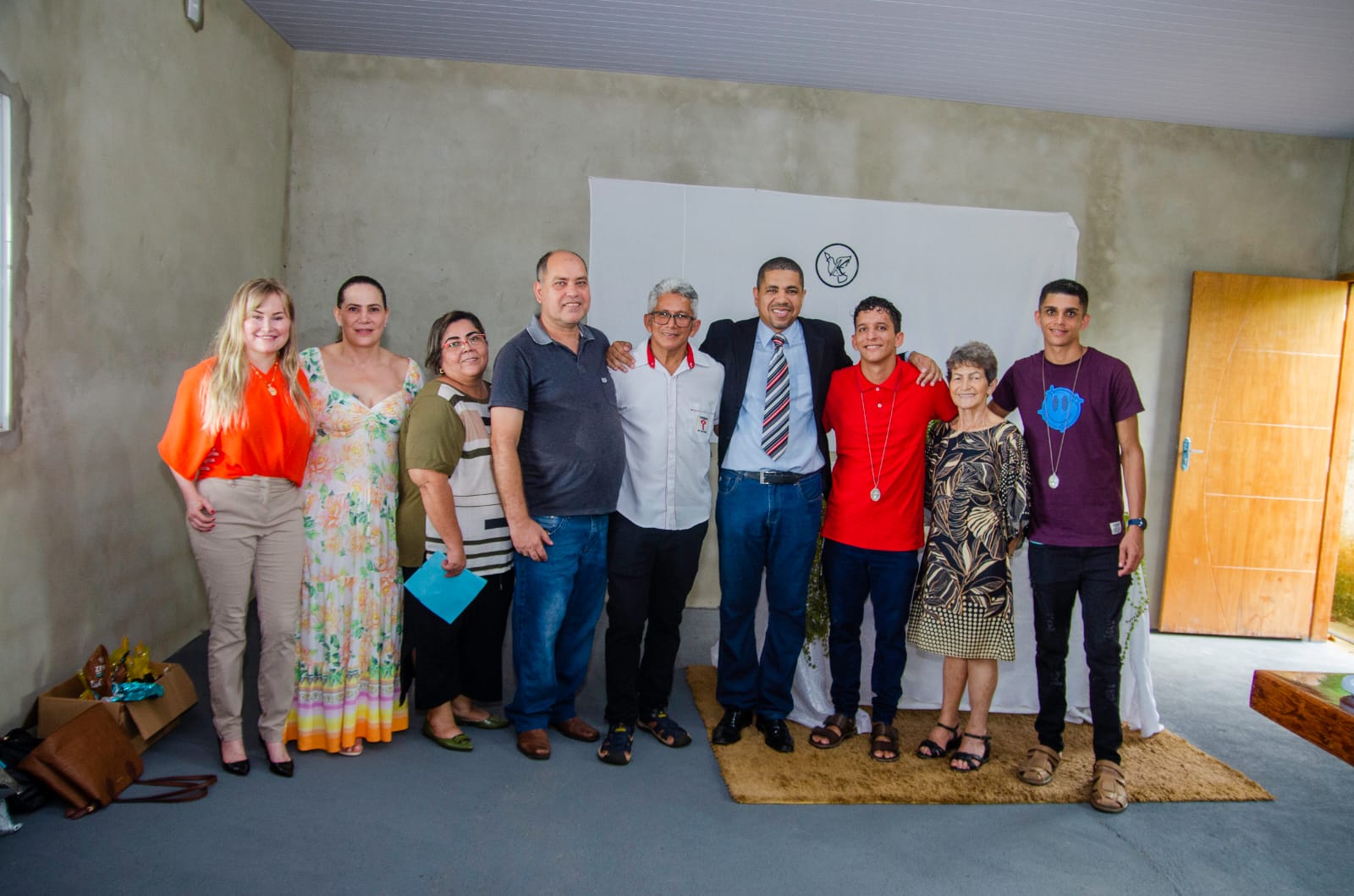 A imagem mostra um grupo de pessoas durante a entrega dos benefícios ao Lar de Idosos