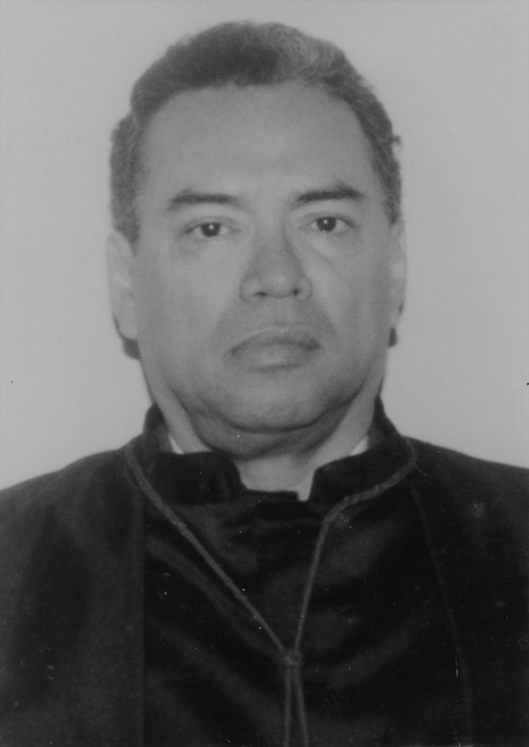 Fotografia em preto e branco, homem pardo, cabelo preto, usando toga