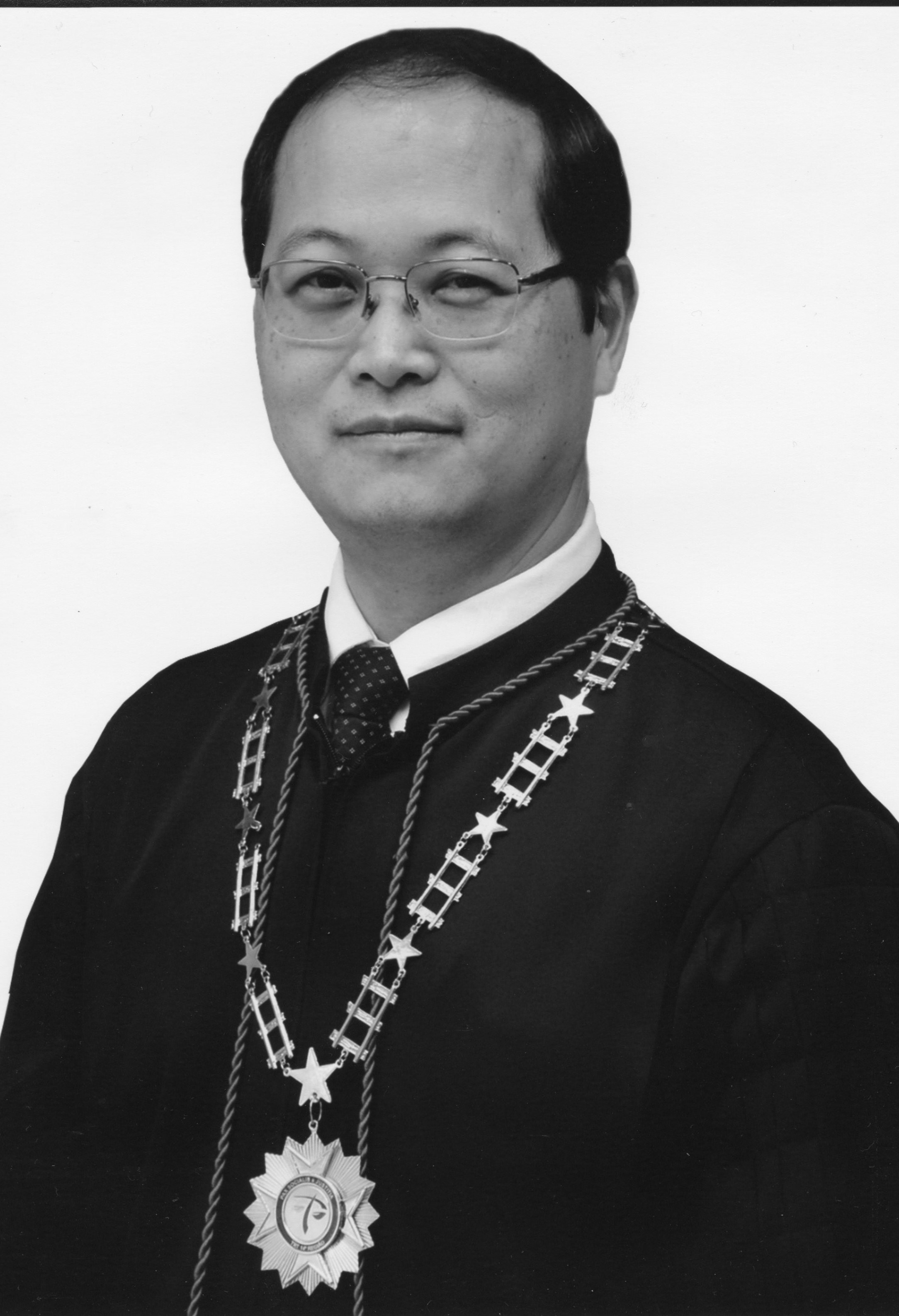 Fotografia em preto e branco, homem japonês, cabelo preto, usando toga.