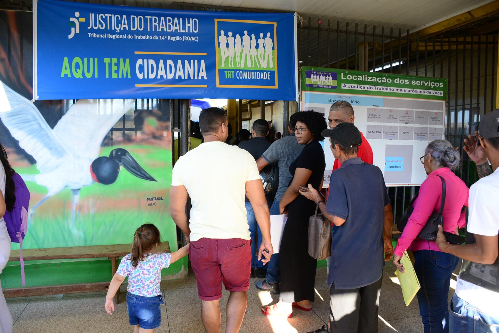 A imagem mostra a população entrando na escola em busca de atendimento.