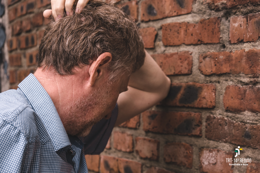 Homem triste em depressão, apoiando-se em uma parede de tijolos. 