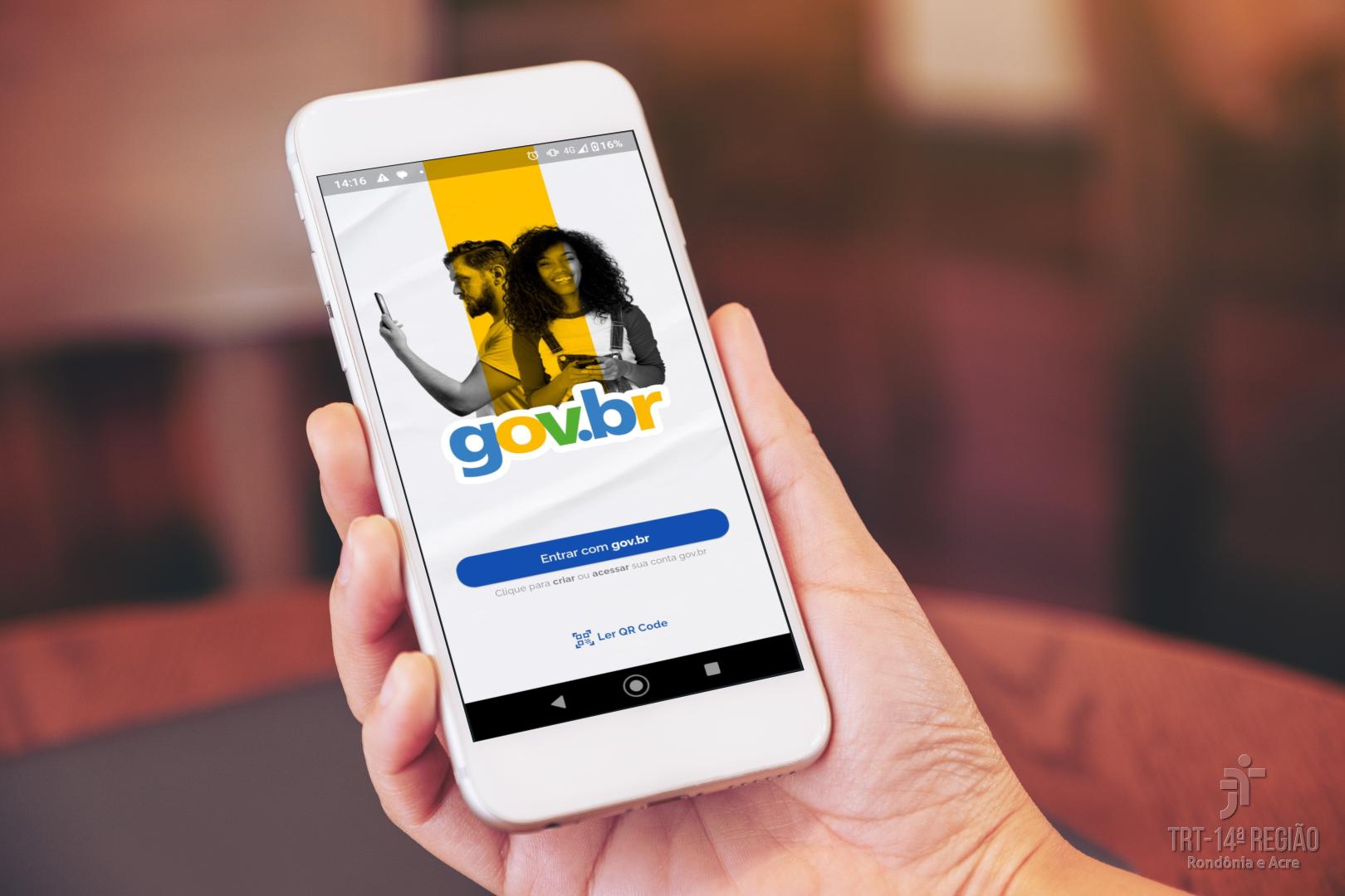 A foto mostra uma mão segurando um celular com o aplicativo gov.br na tela.
