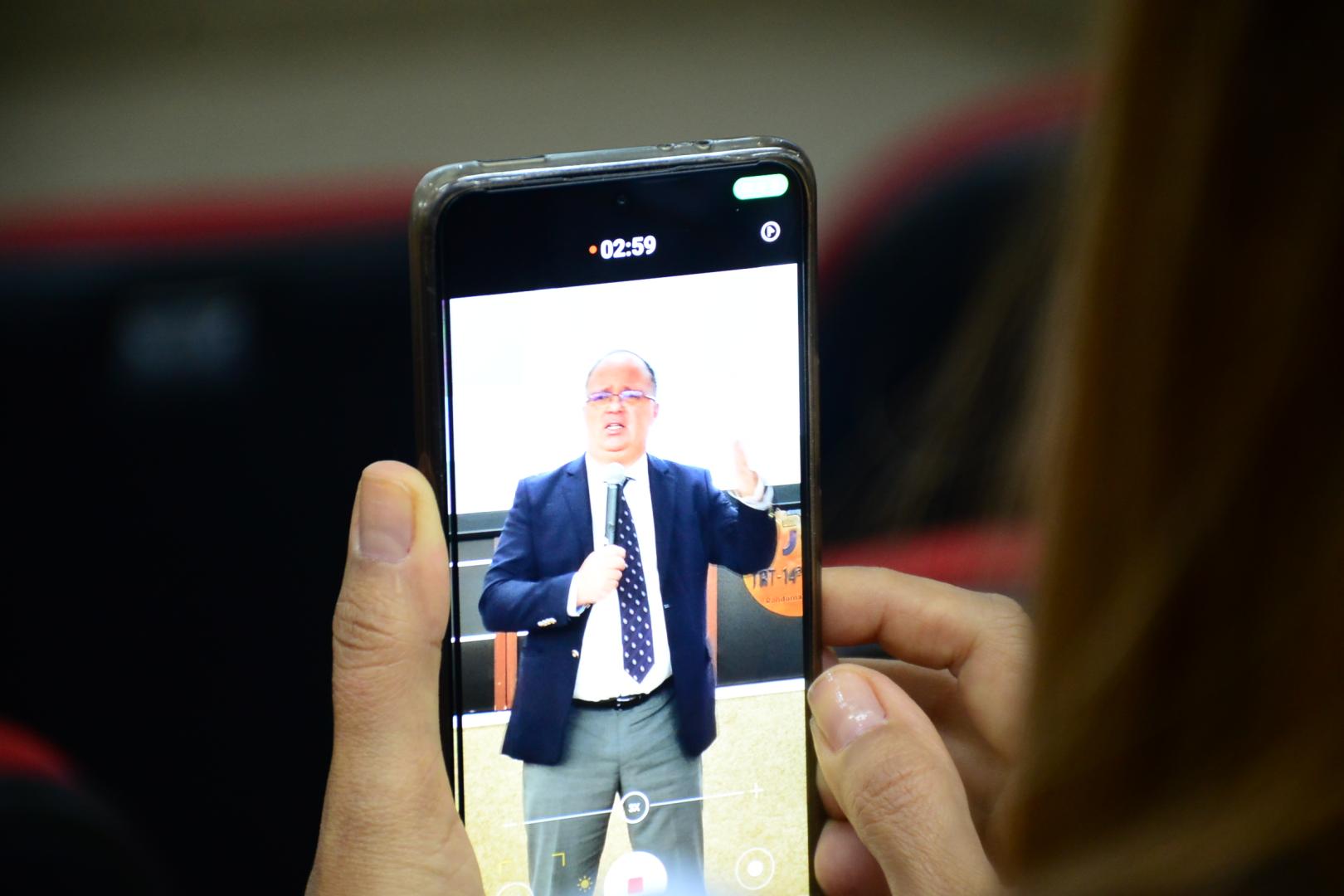 Foto de um celular com a imagem do palestrante