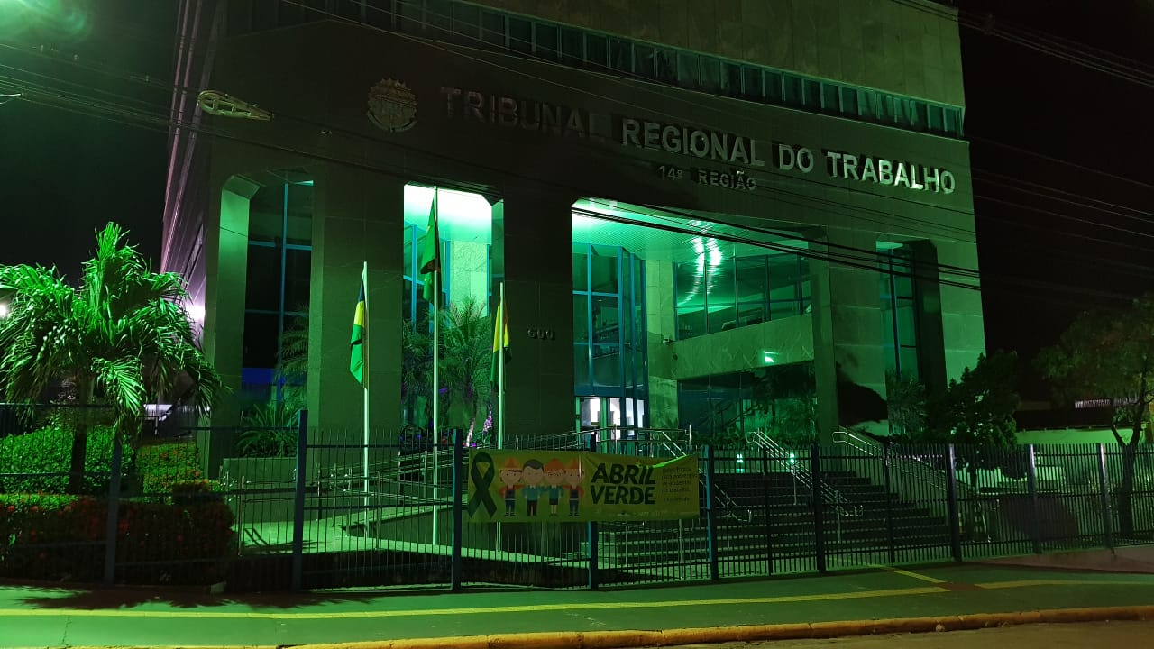 Prédio do Tribunal Regional do Trabalho (RO/AC) com iluminação na cor verde.
