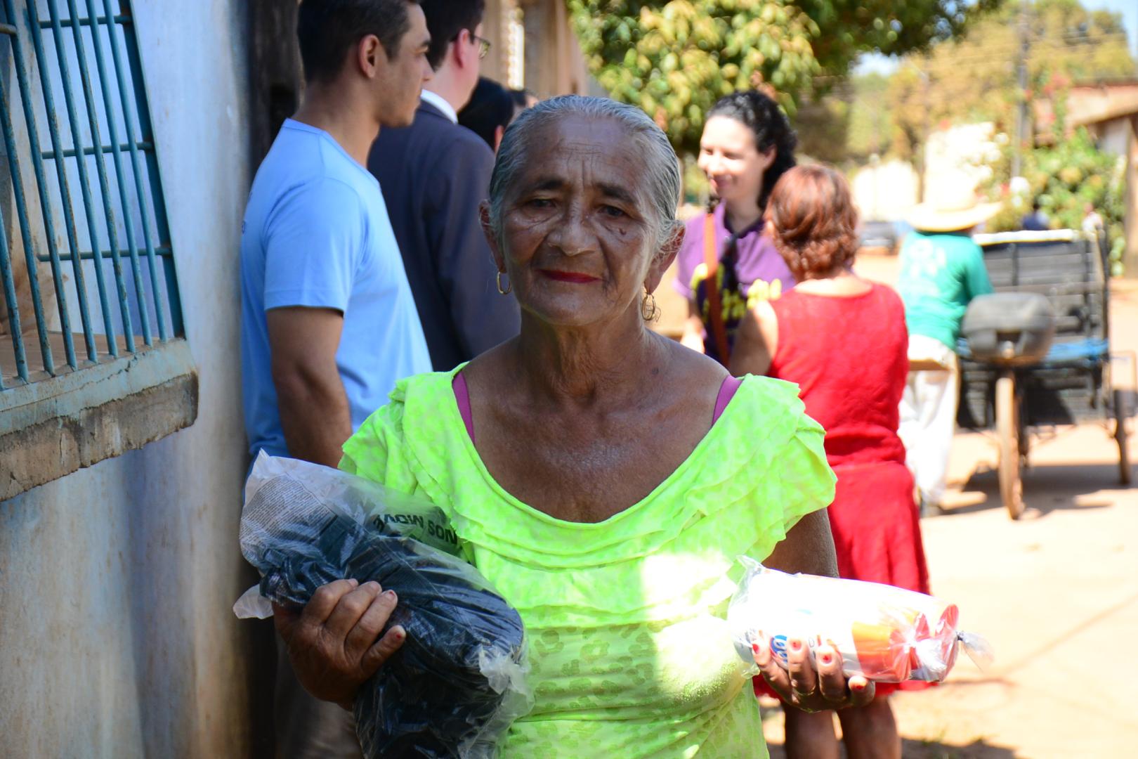 Foto de uma catadora com as botas e o protetor solar nas mãos