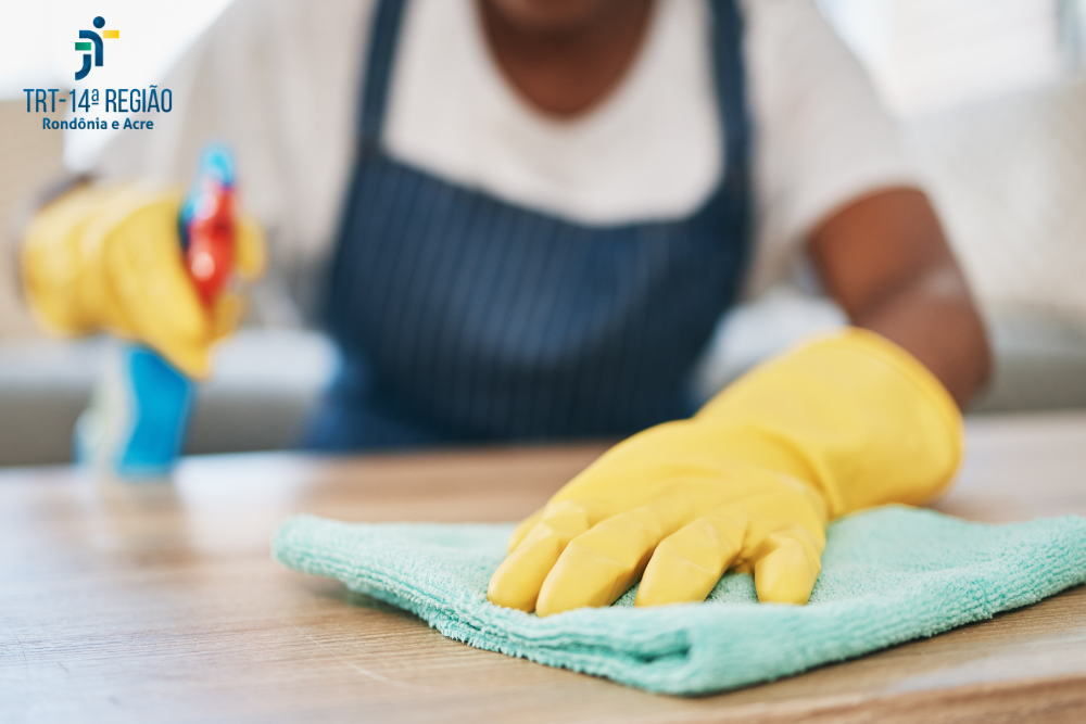 Empregada domestica trabalhando, passa o pano em uma mesa.