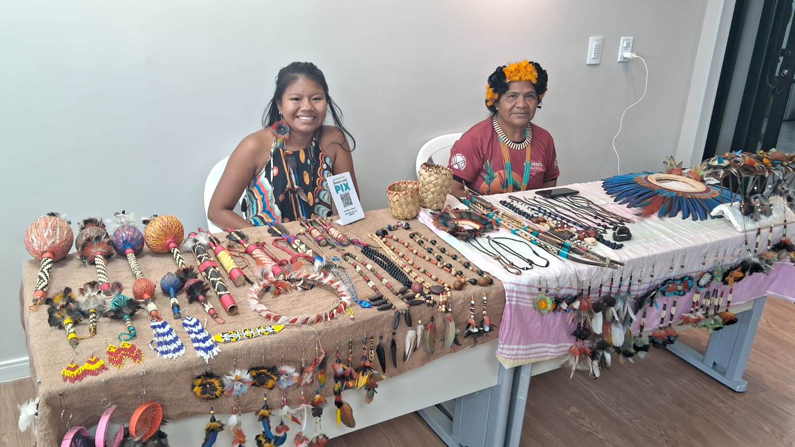 Feira Indígena aberta ao público, com dois representantes dos povos Karitiana expondo e comercializando artes e artesanatos indígena.