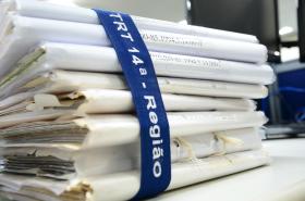 processos físicos empilhados amarrados com uma fita elástica com a inscrição TRT 14ª Região