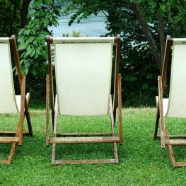 Três cadeiras de espreguiçar em um gramado verde
