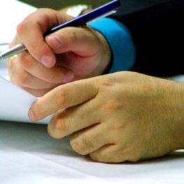Uma pessoa escrevendo com caneta no papel como se estivesse assinando algo